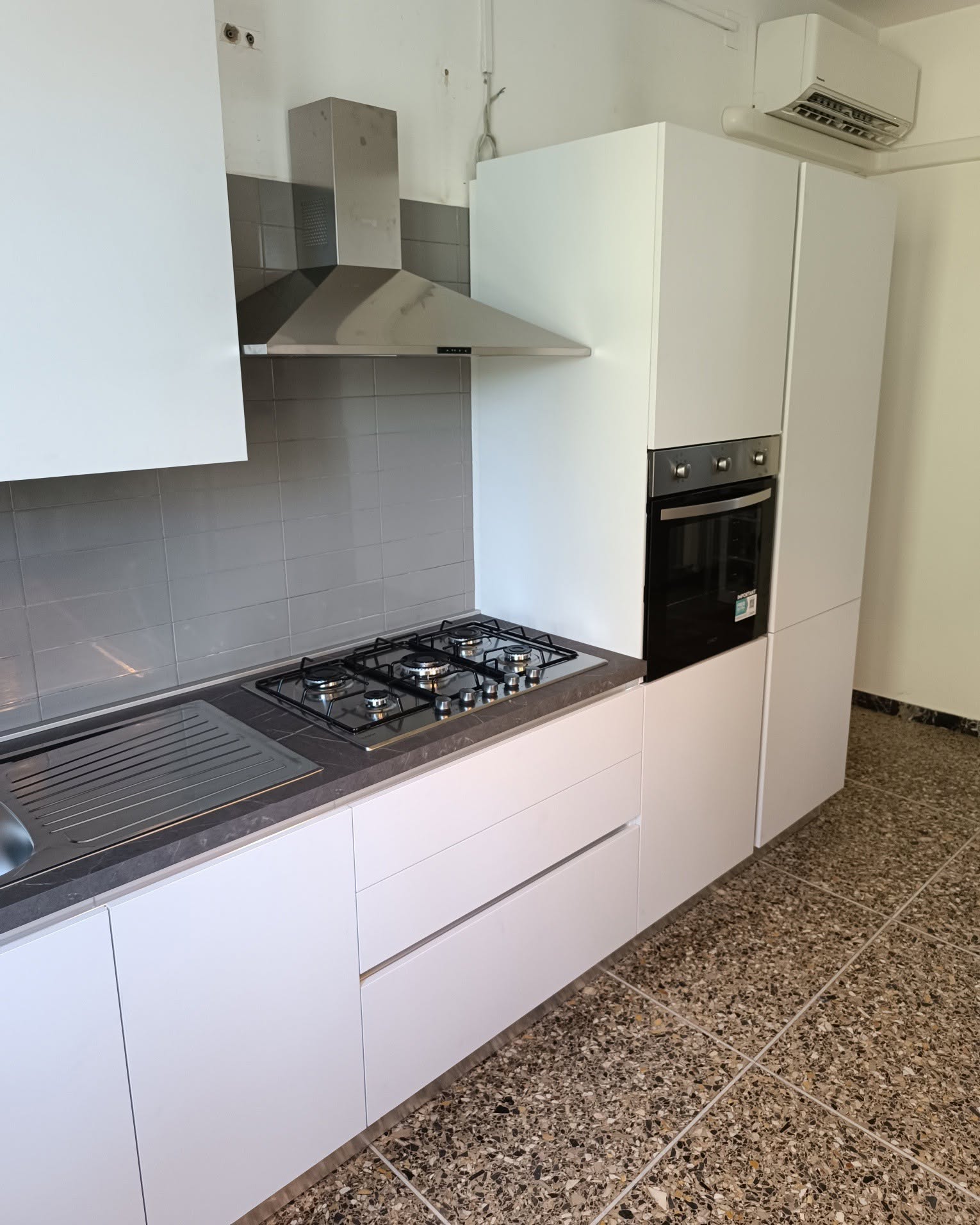 Cucina bianca ad angolo con colonna forno